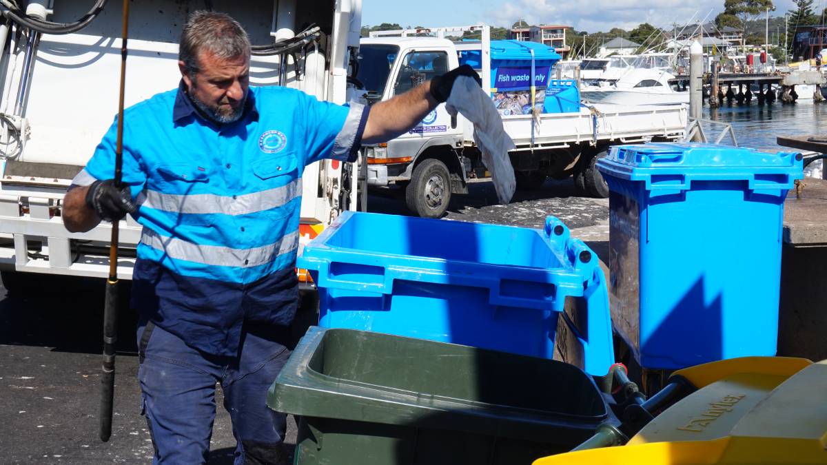 Tim Crane pulls plastic out of the fish waste bins at Bermagui's harbour.